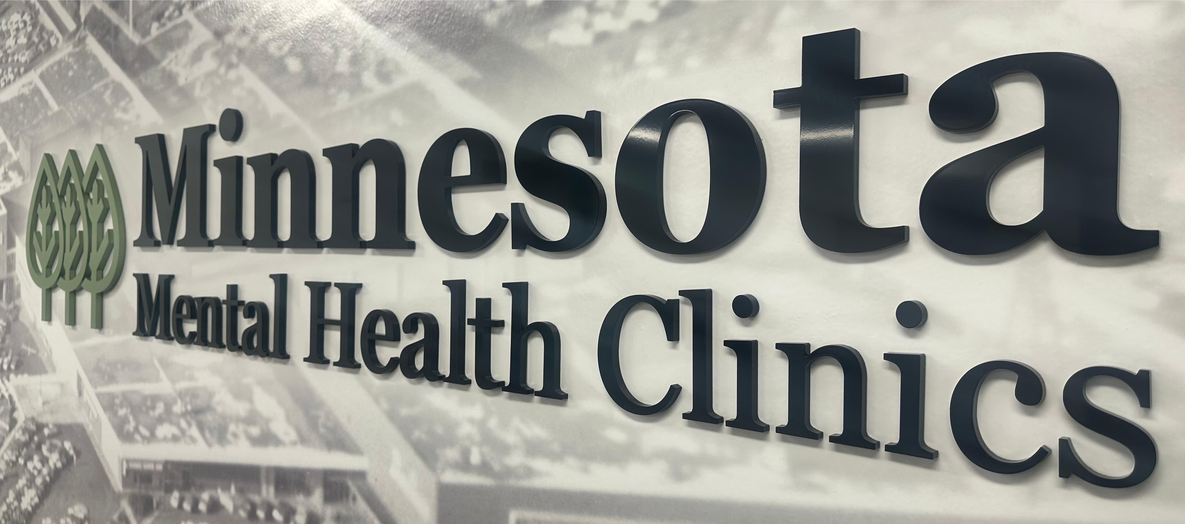 Minnesota Mental Health Clinics lobby sign — the MMHC name and green tree logo mounted on a wall at one of our Minnesota clinic locations