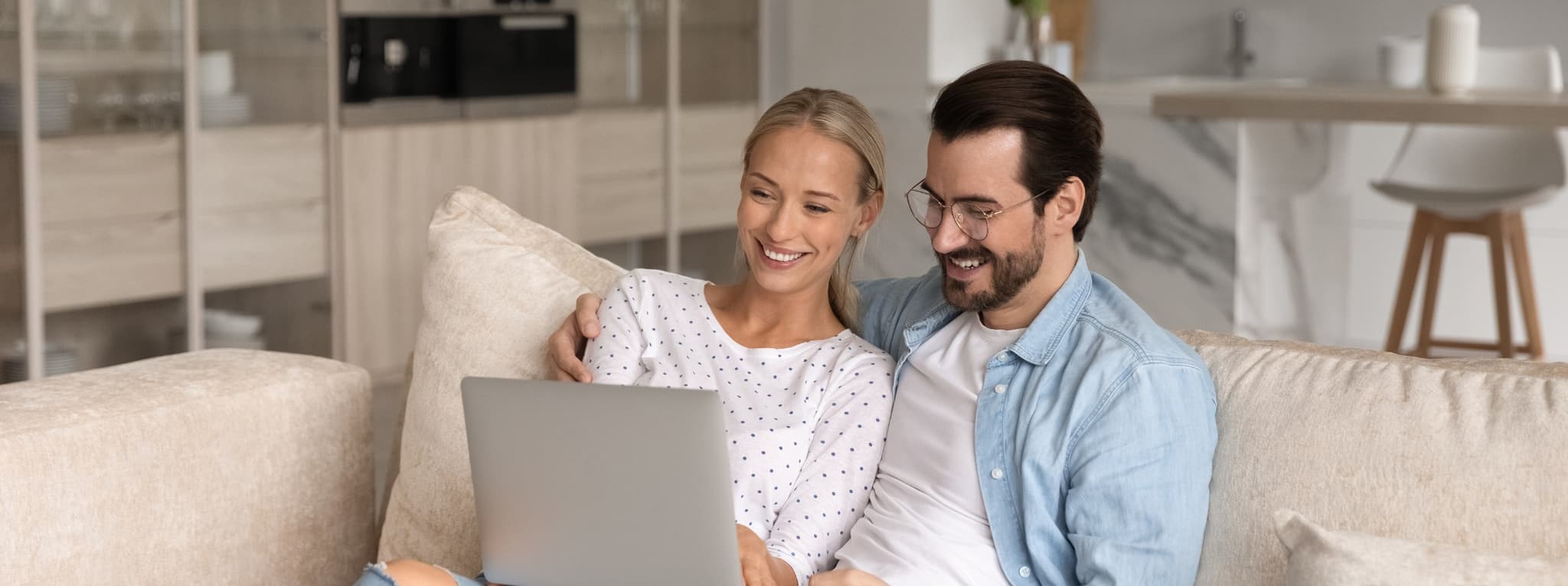 Couple sitting together on a couch sharing a laptop — the warmth and connection that therapy supports