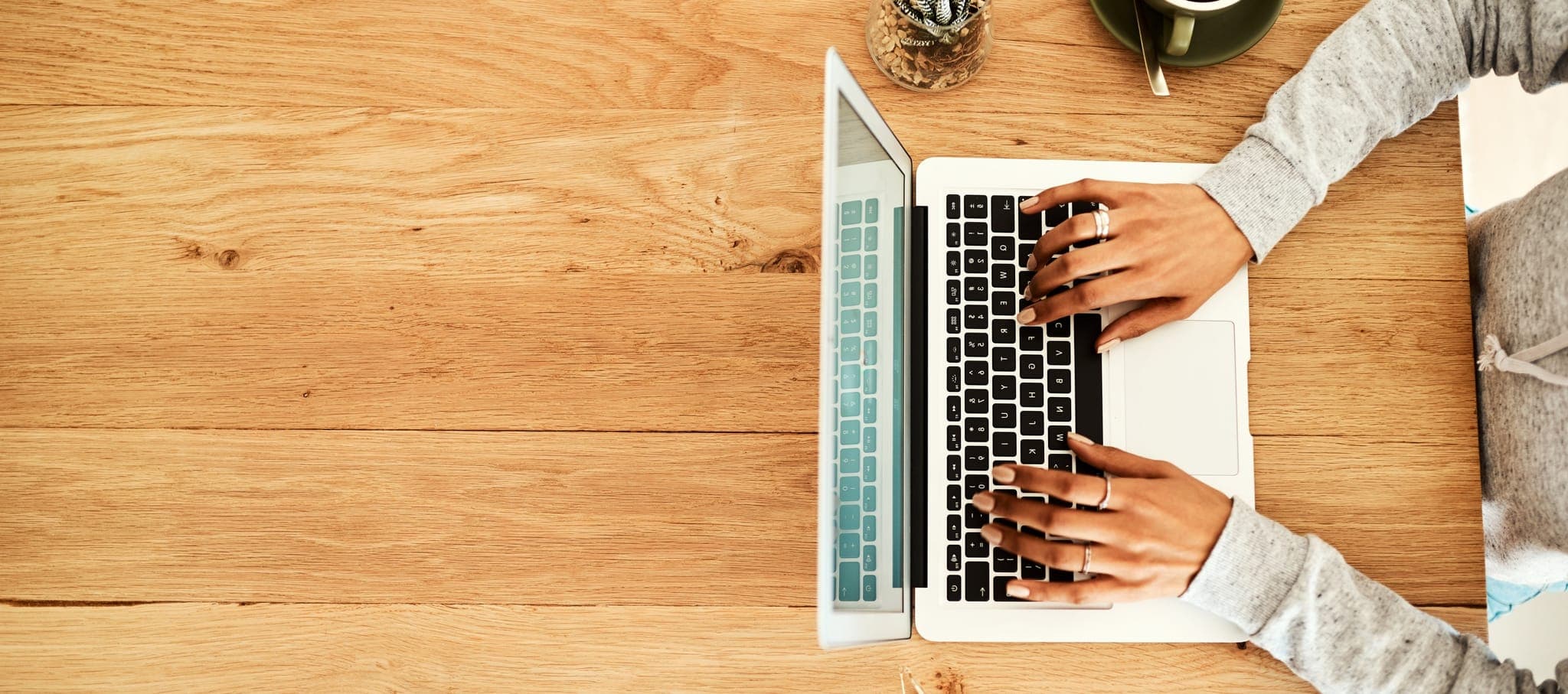 Person typing on a laptop at a wooden desk β Welcome to the MMHC Blog