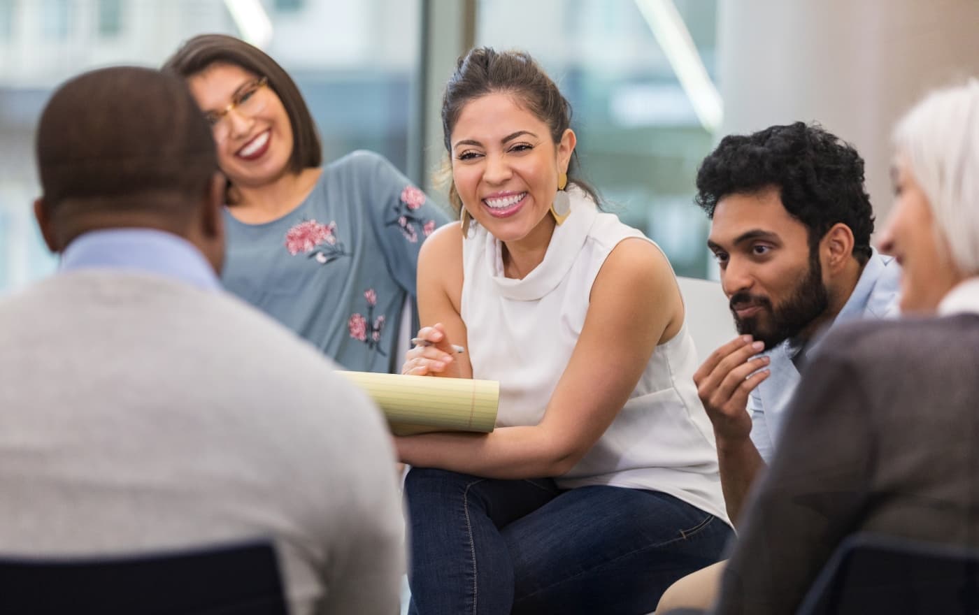 Diverse group of adults smiling and connecting in a group therapy session at Minnesota Mental Health Clinics