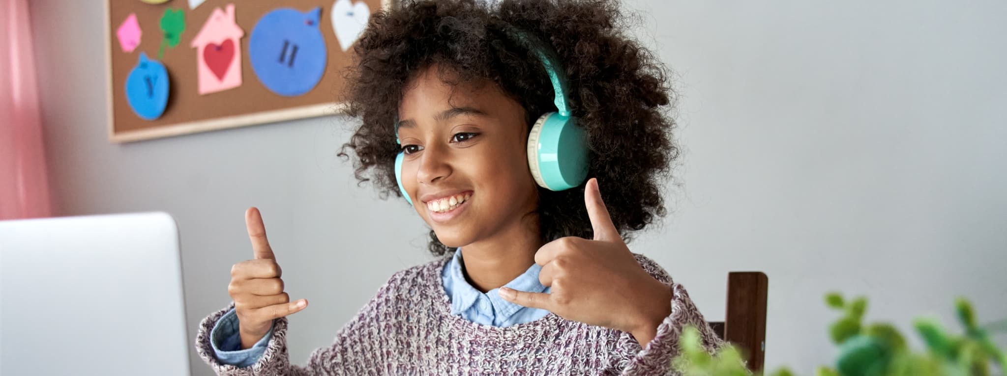Happy child with headphones giving two thumbs up β the confidence children build through therapy at MMHC