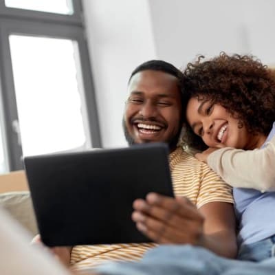 Couple relaxing on the couch with a tablet for virtual mental health care