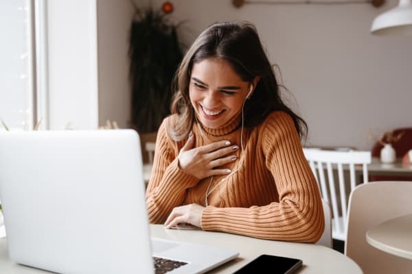 Young woman smiling confidently at her computer during a telehealth therapy session