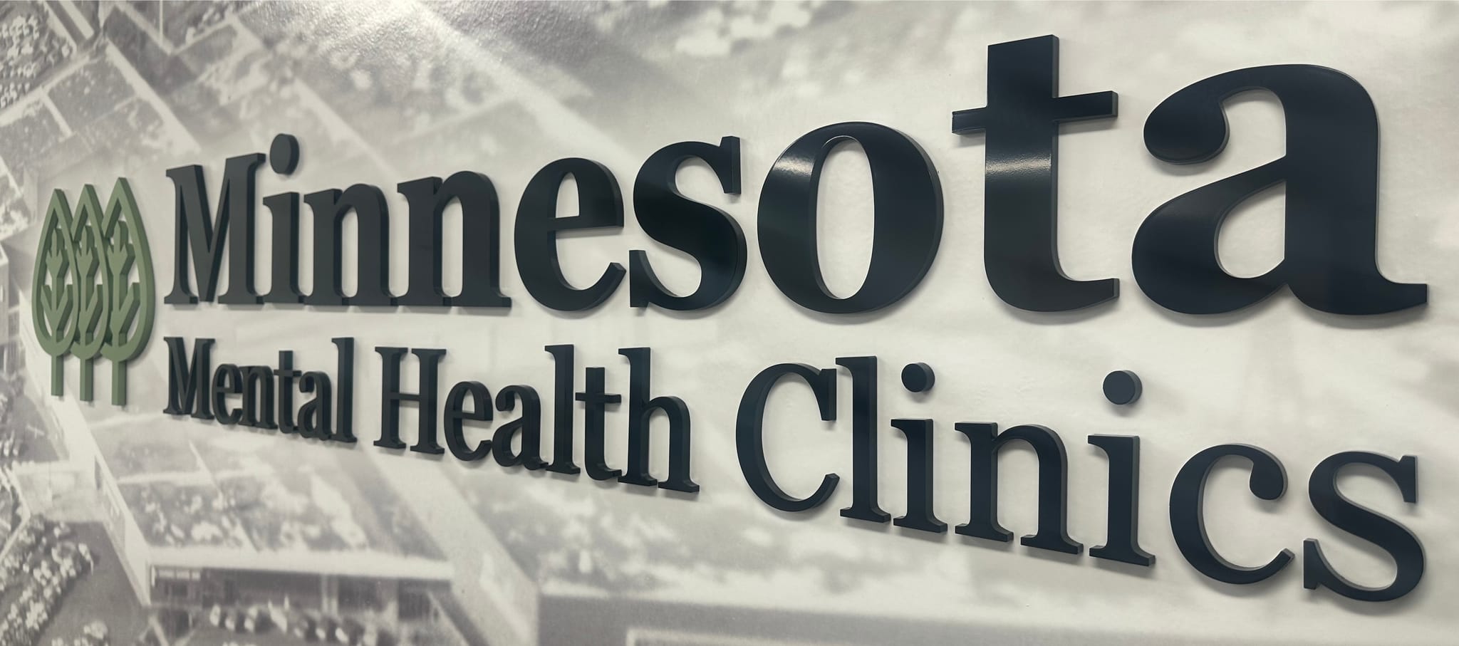 Minnesota Mental Health Clinics lobby sign — the MMHC name and green tree logo mounted on a wall at one of our Minnesota clinic locations